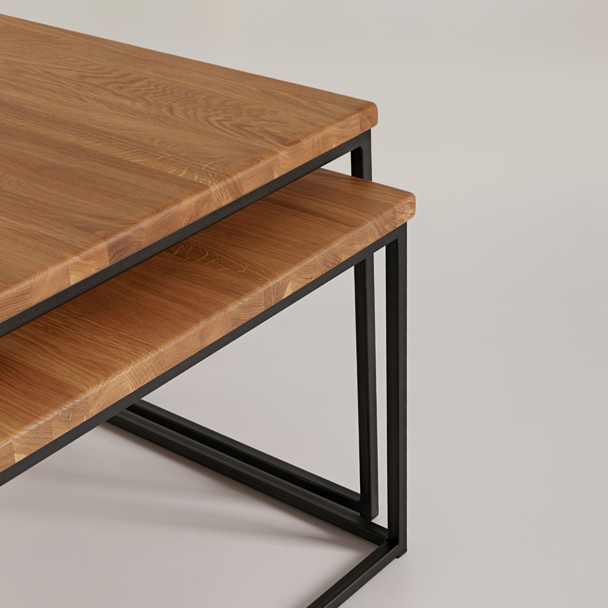 Detailaufnahme eines Couchtisch Sets mit massiver Eiche Tischplatte und schwarzem Metallgestell im minimalistischen Design.