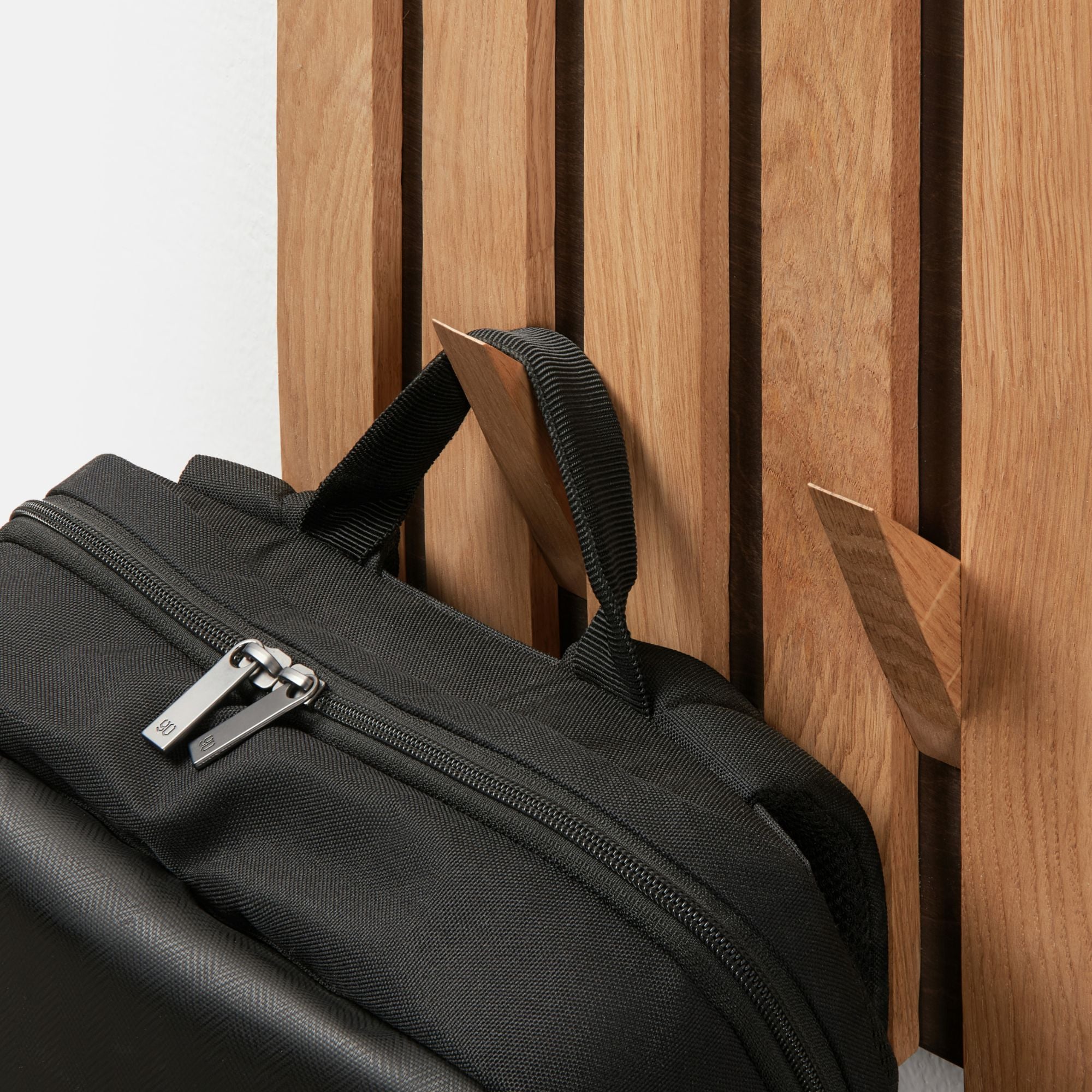 Wandgarderobe aus Eiche mit stabilem Haken, an dem ein schwarzer Rucksack hängt.