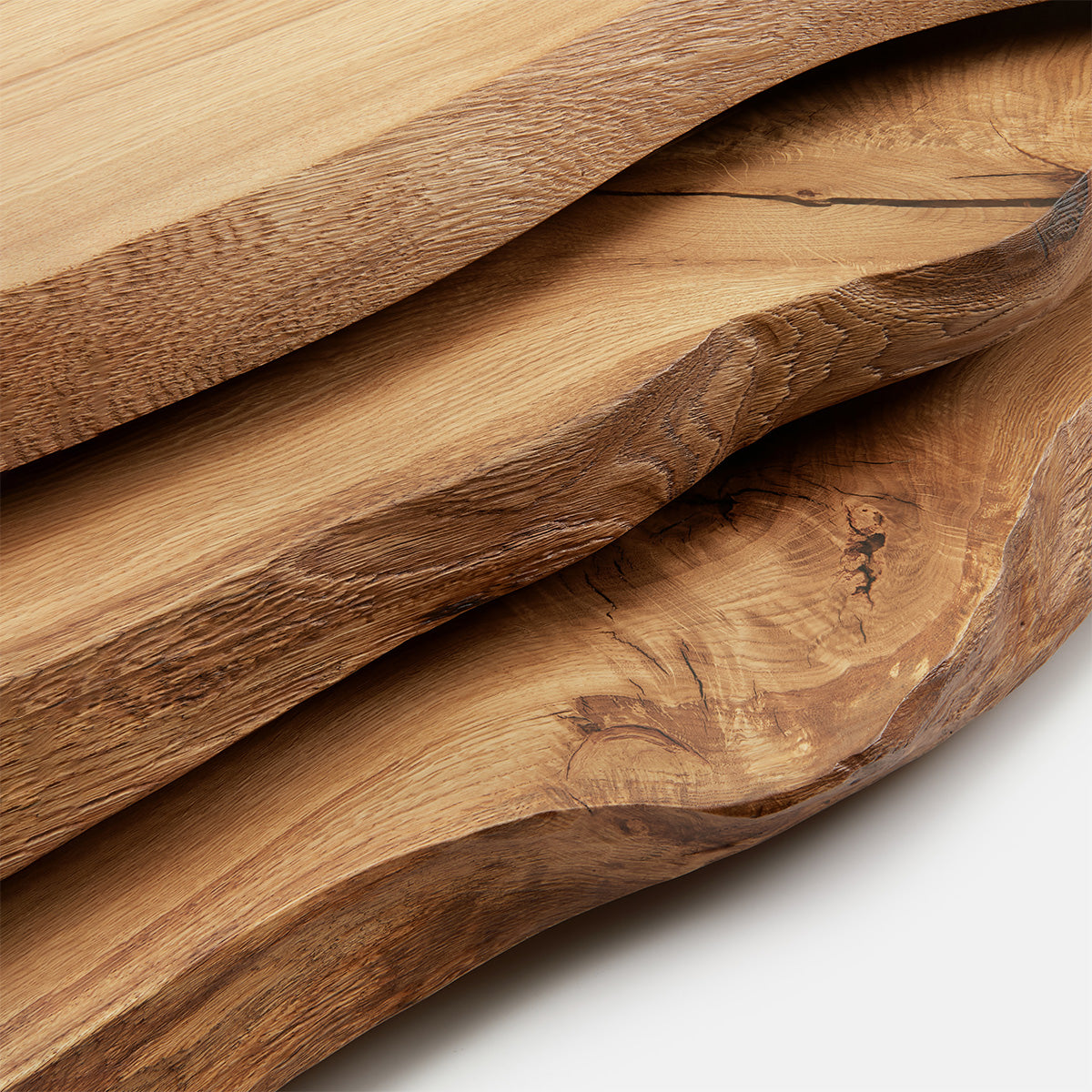 Gestapelte Massivholzplatten aus Eiche mit markanter Naturkante und sichtbarer Maserung in hoher Qualität.