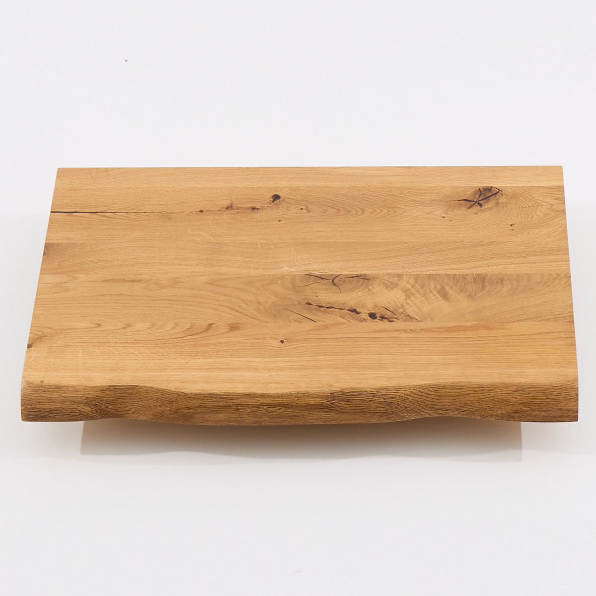 Freigestellte Waschtischplatte aus Eiche mit natürlicher Baumkante und charaktervoller Maserung in Frontansicht.