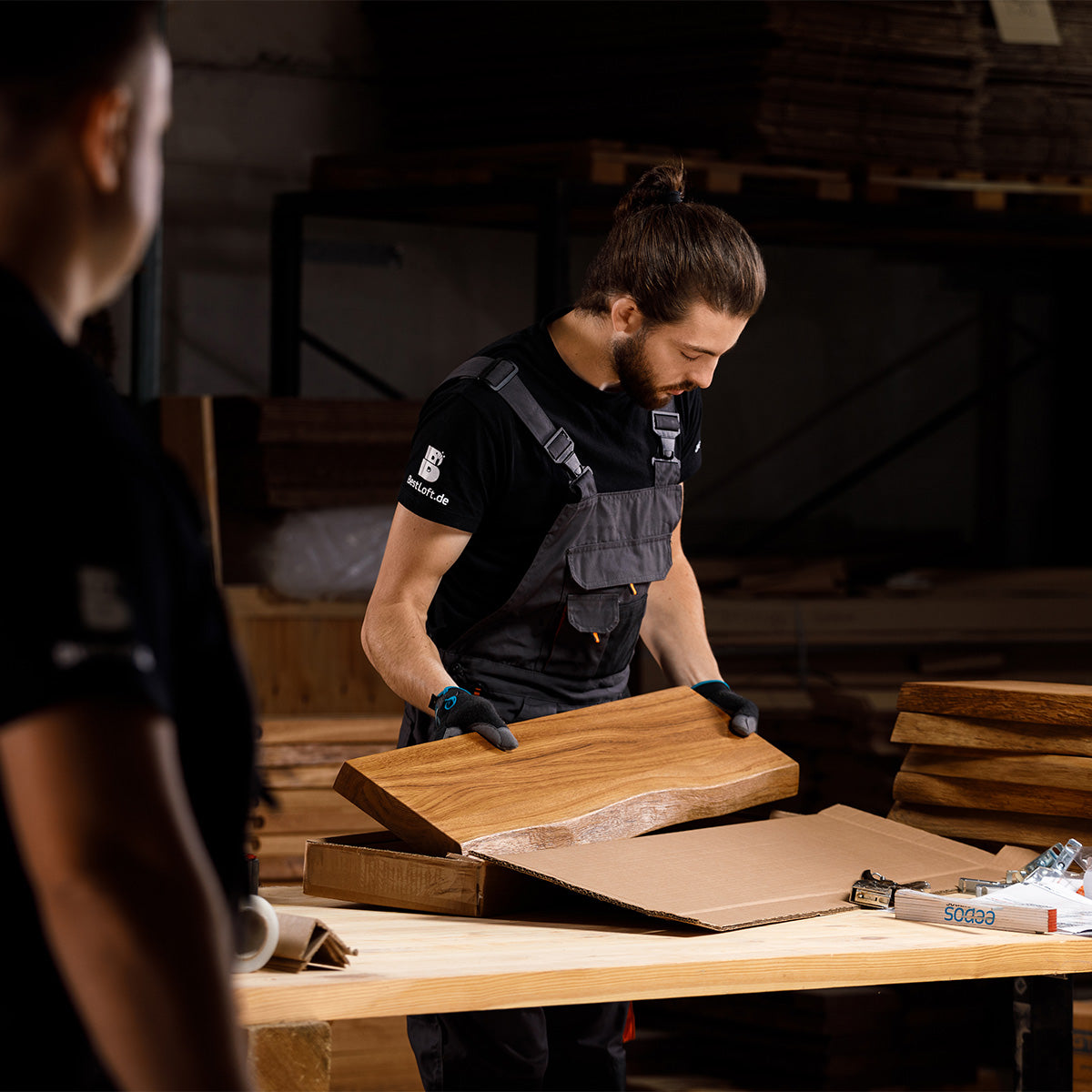 Handwerker prüft eine massive Eichenplatte mit Naturkante und verpackt sie in der Werkstatt für hochwertige Holzprodukte.