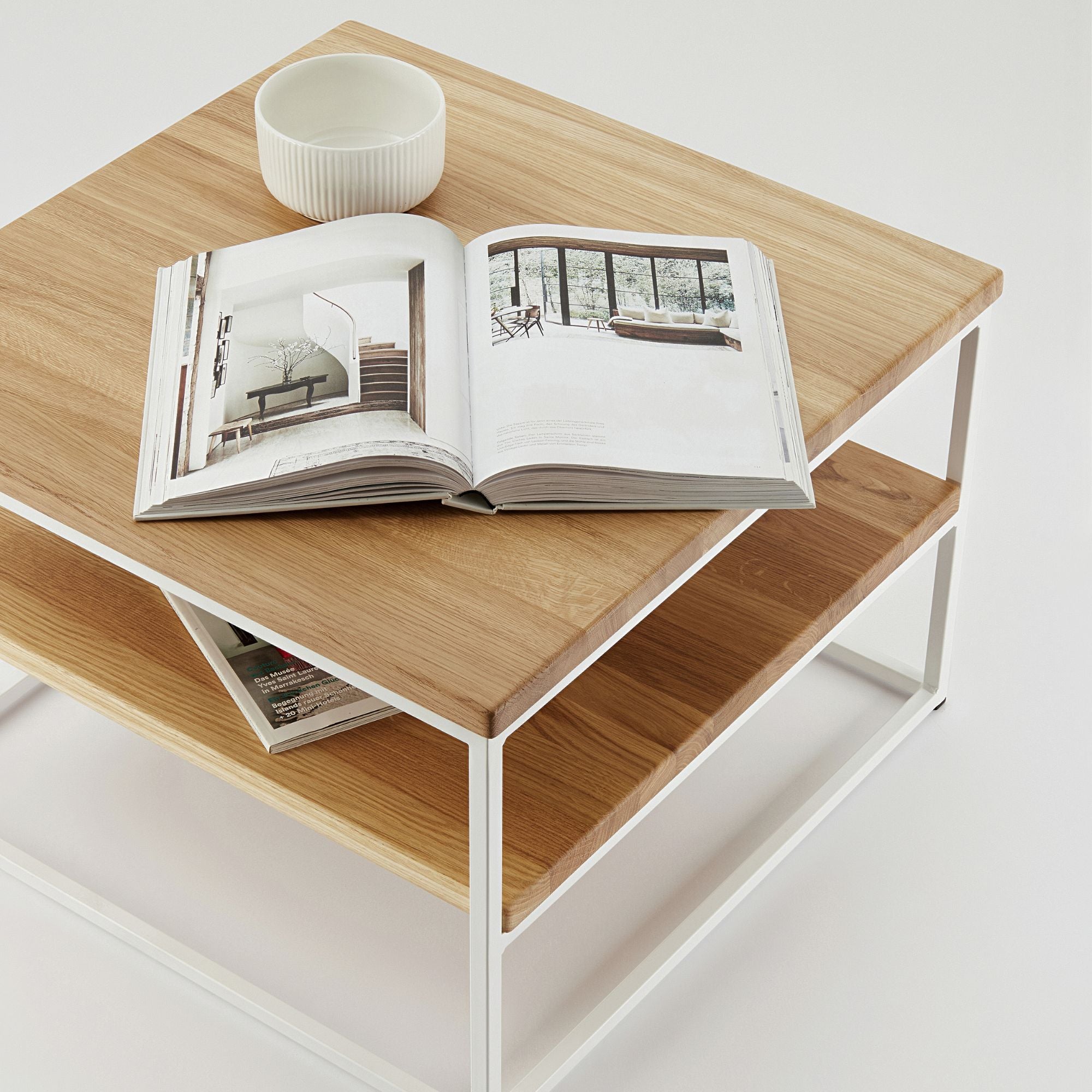 Moderner Beistelltisch aus Eiche Hell mit zusätzlicher Ablage und weißem Metallgestell, dekoriert mit Buch und Schale