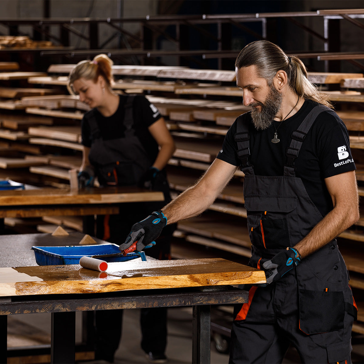 Handwerker trägt Öl auf eine massive Eichenplatte mit Naturkante auf, um die Holzmaserung hervorzuheben.