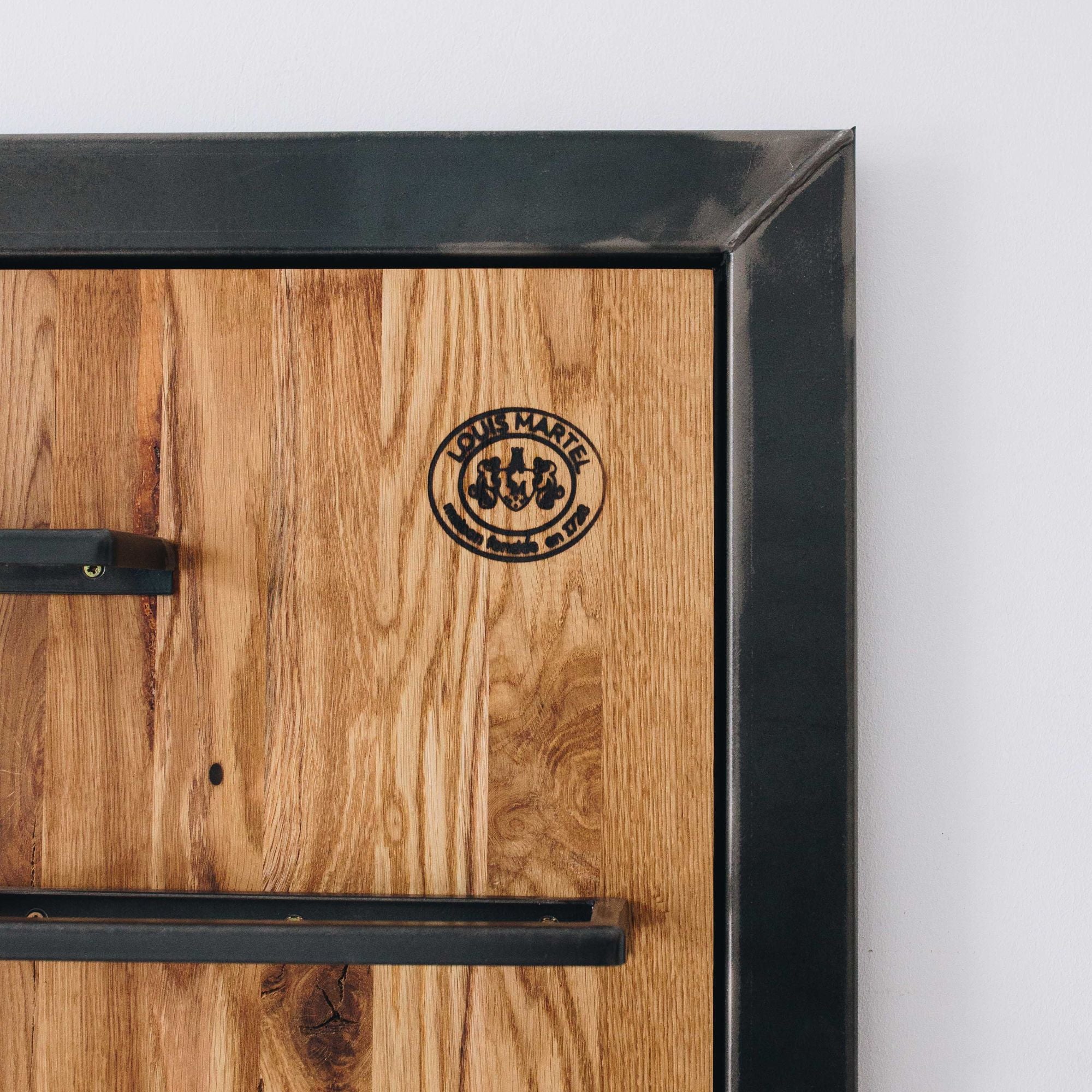 Detail vom Logo „Louis Martel“ auf einem exklusiven Weinregal aus Eiche mit schwarzem Metallrahmen.