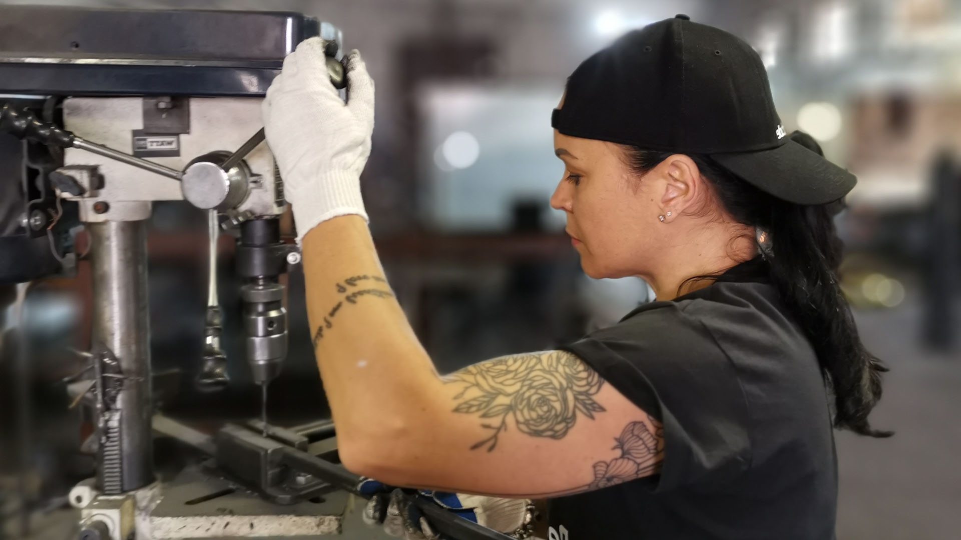 Eine muskulöse Frau an der Maschine fertigt metallische Tischbeine und Bankbeine